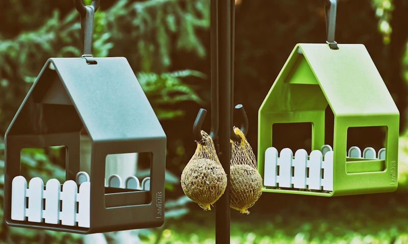 Metal bird feeders hanging off feeding station, brand name seen engraved on feeder