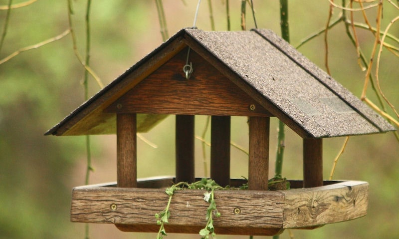 Hanging wooden bird table with roof, supported with four pillars